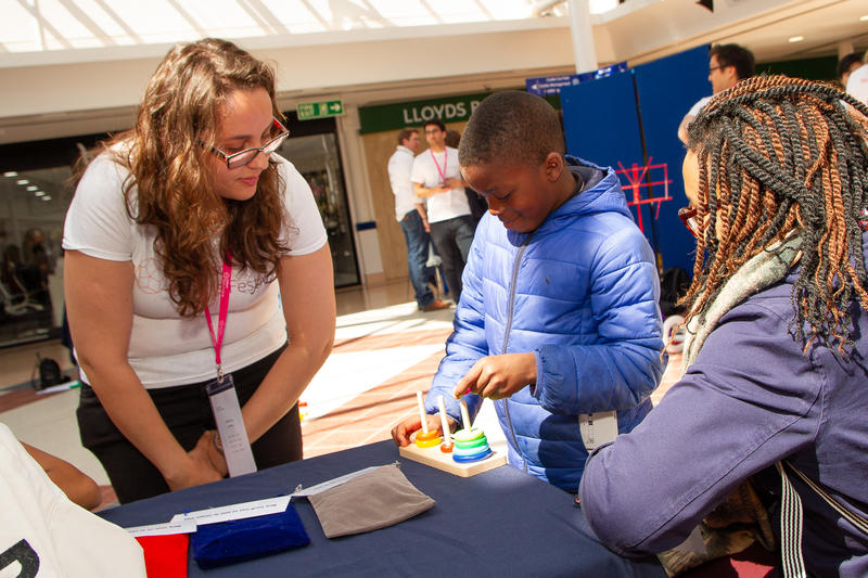 A volunteer watches as a young boy attempts the Tower of Hanoi at the Oxford Maths Festival