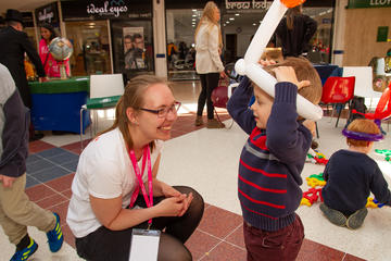 Maths Festival volunteer chatting to a small child with a balloon on his head