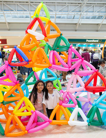 Two children inside a giant sierpinski triangle built from balloons